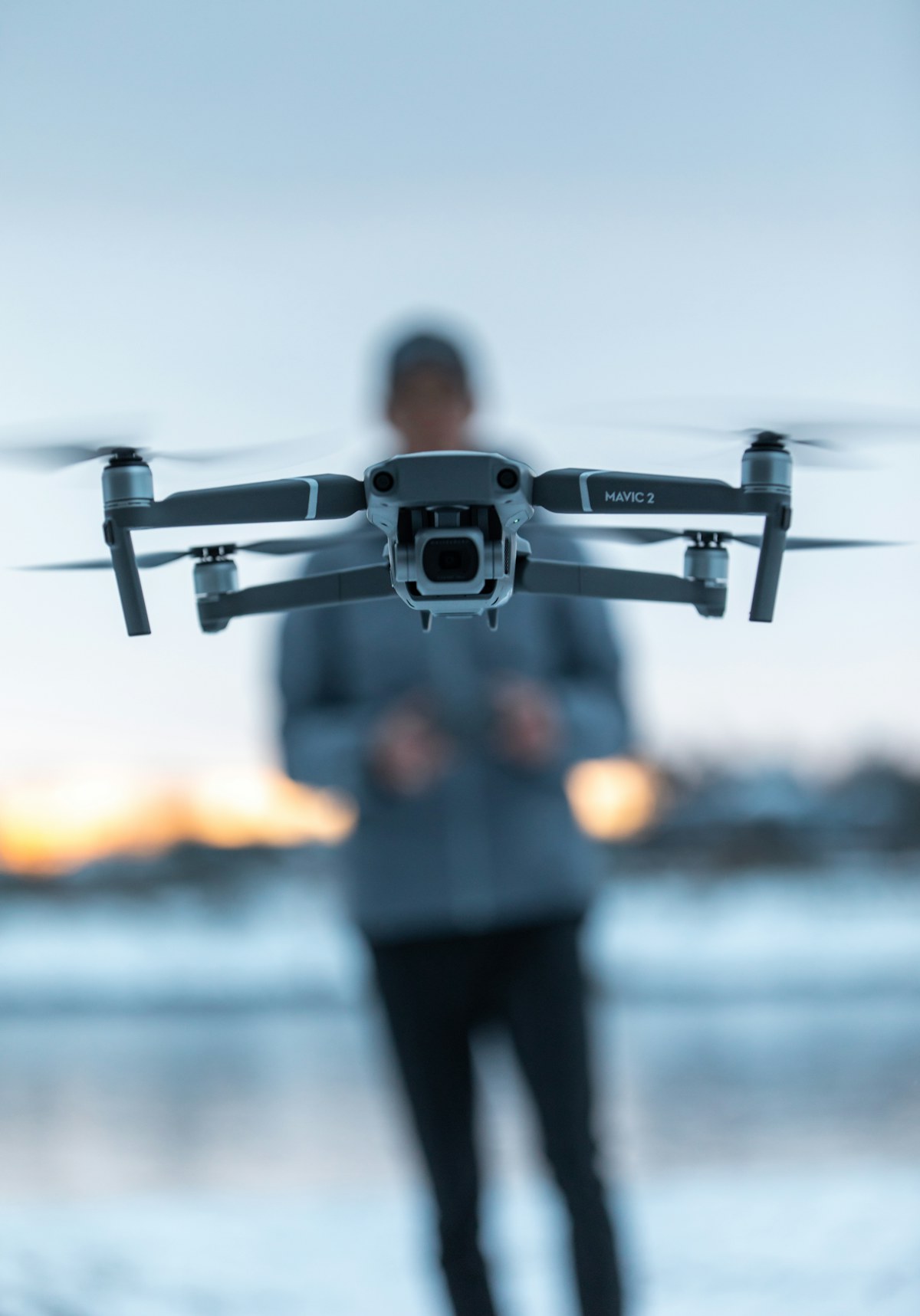 Dronepiloot in het veld met een drone boven zich